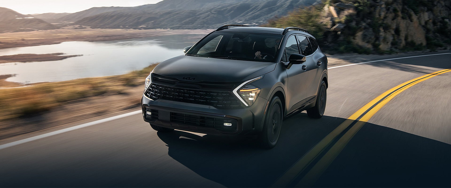 Kia Sportage Hybrid driving on a beautiful sunset road.